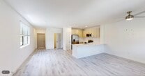 Located at 7301 Lake Bank Loop in Fort Myers, FL, this two-story home offers 3 bedrooms and 3 bathrooms across two well-proportioned floors. The main level features an open-concept living, dining, and kitchen area finished with light wood-style flooring and recessed lighting throughout. The kitchen is equipped with stainless steel appliances — including a French door refrigerator, electric range, and built-in microwave — complemented by light cabinetry and a clean white peninsula countertop that doubles as a breakfast bar. The living area is bright and airy, with a large window drawing in natural light and views of the surrounding greenery. A staircase with crisp white railings leads to the upper level, where the spacious primary bedroom includes sliding glass doors opening to a private balcony with outdoor views, a walk-in closet with wire shelving, and an en-suite bathroom featuring a walk-in shower with marble-style tile, white vanity, and a large mirror. Two additional bedrooms and bathrooms maintain the same clean, modern aesthetic. A dedicated laundry room houses a full-size washer and dryer. The attached garage includes a water heater and electrical panel, offering practical utility. The overall design is fresh, neutral, and move-in ready.