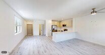 Located at 7301 Lake Bank Loop in Fort Myers, FL, this two-story home offers 3 bedrooms and 3 bathrooms across two well-proportioned floors. The main level features an open-concept living, dining, and kitchen area finished with light wood-style flooring and recessed lighting throughout. The kitchen is equipped with stainless steel appliances — including a French door refrigerator, electric range, and built-in microwave — complemented by light cabinetry and a clean white peninsula countertop that doubles as a breakfast bar. The living area is bright and airy, with a large window drawing in natural light and views of the surrounding greenery. A staircase with crisp white railings leads to the upper level, where the spacious primary bedroom includes sliding glass doors opening to a private balcony with outdoor views, a walk-in closet with wire shelving, and an en-suite bathroom featuring a walk-in shower with marble-style tile, white vanity, and a large mirror. Two additional bedrooms and bathrooms maintain the same clean, modern aesthetic. A dedicated laundry room houses a full-size washer and dryer. The attached garage includes a water heater and electrical panel, offering practical utility. The overall design is fresh, neutral, and move-in ready.