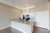 Located at 18248 W 12 Mile Rd in Southfield, MI, this well-appointed one-bedroom, one-bathroom unit offers a thoughtfully designed single-floor layout. The open-concept living, dining, and kitchen area forms the heart of the home, anchored by a large center island with granite countertops and an integrated sink. The kitchen is equipped with stainless steel appliances, including a refrigerator, range, microwave, and dishwasher, alongside crisp white cabinetry that maximizes storage. Dark hardwood-style flooring runs throughout the main living areas, complementing the neutral warm-toned walls. The living room is bathed in natural light through oversized windows and a glass door that opens to a private patio with views of the surrounding building exterior. The bedroom features plush carpeting, a generous window for natural light, and access to two closets for ample storage. The bathroom is finished with large-format tile flooring and wall surround in the tub/shower combination, paired with a granite-topped vanity. A dedicated laundry area and a hallway complete the functional layout, making this a well-rounded and move-in-ready residence.