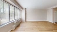 Located at 3900 16th St NW, Unit 106, in Washington, DC, this single-floor unit offers a practical and well-organized layout comprising a living room, kitchen, bathroom, and closet. Throughout the space, light hardwood flooring lends a clean, consistent aesthetic that ties each room together.

The living room is a bright, open area anchored by a wide bank of windows that invite generous natural light and offer leafy outdoor views. Neutral-toned walls and clean white baseboards complement the airy feel of the room, while a baseboard heating unit sits discreetly beneath the windows.

The kitchen is efficiently laid out with white cabinetry, granite-look countertops, and white appliances including a gas range and refrigerator. The space is functional and straightforward, making good use of the available footprint.

The bathroom features classic white subway tile wainscoting, a combined tub and shower, a pedestal-style sink with chrome fixtures, a mirrored medicine cabinet, and marble-look tile flooring. A well-lit vanity light above the mirror provides clear, practical illumination.

A hallway connects the rooms, offering access to a dedicated closet for storage. The overall palette of warm whites and soft beiges creates a calm, neutral ambiance throughout this conveniently located Washington, DC unit.