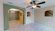 This two-story home presents a practical and comfortable layout with thoughtfully designed living spaces throughout both floors. The main living area is spacious and open, featuring light ceramic tile flooring, ceiling fans with integrated lighting, and a neutral color palette accented by sage green walls. Distinctive arched doorways connect the living spaces, adding architectural character, while built-in arched wall niches provide decorative interest. Natural light filters in through windows, contributing to a bright and airy atmosphere.

The kitchen is equipped with warm oak cabinetry, a tile backsplash, and white appliances including a range, built-in microwave, and refrigerator with a water and ice dispenser. A pass-through window connects the kitchen to the adjacent living area. The dining area features tile flooring and an elegant chandelier overhead, with access to a dedicated laundry space.

Bedrooms are carpeted and offer generous closet storage, with multiple reach-in closets featuring built-in shelving and hanging rods. Ceiling fans are present in the bedrooms as well. The bathrooms include oak vanities with integrated sinks, overhead lighting, and full tub and shower combinations with clean white surrounds.