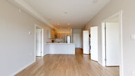 This well-appointed 2-bedroom, 1-bathroom unit offers a thoughtfully designed open-concept layout that seamlessly connects the living area and kitchen. Light wood laminate flooring flows throughout the space, creating a warm, cohesive aesthetic. The kitchen is a standout feature, equipped with stainless steel appliances — including a refrigerator, range, and over-the-range microwave — complemented by light wood cabinetry and granite-style countertops that extend into a peninsula, ideal for casual dining or meal prep. Recessed lighting illuminates the kitchen and living area efficiently. In-unit laundry is conveniently tucked into a dedicated closet near the main living space. The two bedrooms are bright and well-sized, with the primary bedroom offering a large window that frames views of the surrounding neighborhood and fills the room with natural light. Both rooms feature the same warm wood flooring found throughout. The bathroom includes a walk-in shower, tile flooring, and a vanity with matching stone countertop. A private balcony accessible from the unit provides outdoor space with open views of the residential neighborhood, framed by mature trees. The overall aesthetic is clean, modern, and move-in ready.