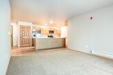 Located at 331 Cedar Bird Ln in Holmen, WI, this single-floor home offers a thoughtfully designed layout with a clean, modern aesthetic. The open-concept kitchen and living area serves as the central hub of the home, where light wood cabinetry, stone-look countertops with subtle veining, and a full suite of stainless steel appliances — including a French door refrigerator, range, and over-the-range microwave — create a functional and visually cohesive space. A generously sized kitchen island with a built-in sink provides additional workspace and serves as a natural gathering point. Recessed lighting illuminates the kitchen, complementing the light hardwood-style flooring that extends throughout the main areas.

The living space adjoins the kitchen seamlessly, featuring plush carpeting that adds warmth underfoot. Additional rooms continue the neutral color palette with soft gray walls and coordinating carpet. A dedicated utility room houses a stacked washer and dryer alongside wire shelving and a water heater, maximizing efficiency. The bathroom features a tub-shower combination framed by mosaic tile accents in charcoal and gray tones, paired with oil-rubbed bronze fixtures for a refined finishing touch.