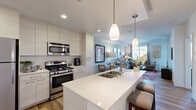 Located at 7777 Westside Drive in San Diego, CA, this thoughtfully designed one-bedroom, one-bathroom residence offers a functional and stylish single-floor layout. The open-concept kitchen and living area serves as the heart of the home, featuring a large white quartz waterfall island with an undermount double sink, sleek white flat-front cabinetry extending to the ceiling, stainless steel appliances including a gas range, microwave, refrigerator, and dishwasher, and warm wood-look flooring throughout. Pendant lighting over the island adds a modern touch. The living room is bright and welcoming, with large windows and a private door leading to an outdoor balcony, allowing generous natural light to fill the space. The bedroom offers plush carpet flooring, a ceiling fan, and a window with outdoor views, providing a comfortable retreat. It connects directly to the full bathroom, which features wood-look flooring, a white vanity with quartz countertop, a large mirror, and a shower-tub combination. A dedicated closet and hallway complete the layout, offering practical storage solutions. Throughout the residence, a neutral color palette, recessed lighting, and clean architectural lines create a cohesive, modern aesthetic.