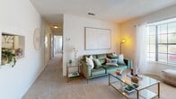 This single-floor residence offers a thoughtfully designed layout that balances comfort and functionality across multiple rooms. The living area serves as the heart of the home, featuring plush carpeted flooring, a large bay window that draws in natural light, and open sightlines into a connecting hallway that leads to the private quarters. A dedicated dining nook sits adjacent to the kitchen, accented by a ceiling fan and framed wall art, creating an inviting space for meals and gatherings. The kitchen is outfitted with warm wood cabinetry, granite-style countertops, black appliances including a range, microwave, and refrigerator, and durable hardwood-style flooring that adds a clean, practical touch. Multiple bedrooms are carpeted and bright, each featuring windows with sheer curtains that invite outdoor views and natural light. The bedrooms offer ample space for full bedroom furniture sets, with neutral wall tones that complement a variety of décor styles. The two full bathrooms are finished with rich wood cabinetry, granite-style vanity countertops, hardwood-style flooring, and tub-shower combinations, providing both style and practicality. Throughout the residence, a consistent warm, neutral palette and textured ceilings contribute to a cohesive and comfortable ambiance.