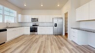 The Haven is a thoughtfully designed two-story residence offering three bedrooms and two and a half bathrooms across a generously sized floor plan. The exterior presents a classic red brick facade with white-trimmed entry, a wall-mounted lantern light, and a welcoming front entrance that opens into a straight hallway with durable wood-look flooring.

The kitchen features crisp white shaker cabinetry, granite countertops, stainless steel appliances including a dishwasher and range, a tile backsplash, and a window above the sink that brings in natural light. Bedrooms are finished with either soft carpeting or wood-look flooring, with ceiling fans and wall-mounted mini-split units for individual climate control. A spacious walk-in closet with wire shelving provides ample storage in the primary suite.

The full bathrooms include dual-sink vanities topped with granite countertops, white cabinetry, and wood-look flooring. Double panel doors throughout add a clean, refined detail. The attached garage features an epoxy-coated floor and an automatic opener, providing secure, practical parking and additional storage space.