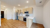 Located at 11816 Wayzata Blvd in Minnetonka, MN, this thoughtfully designed one-bedroom, one-bathroom unit offers a clean, contemporary aesthetic throughout its efficiently arranged single floor. The open-concept kitchen and living area serves as the heart of the unit, featuring light wood cabinetry with matte black hardware, a white subway tile backsplash, bright white quartz countertops, and a full suite of stainless steel appliances including a refrigerator, electric range, microwave, and dishwasher. A peninsula provides additional counter space and naturally defines the transition between the kitchen and living area. Warm-toned luxury vinyl plank flooring runs throughout the main living spaces, complementing the unit's bright, neutral palette and recessed lighting overhead. A sliding glass door brings in natural light and provides outdoor access from the living area. The bedroom is a comfortable, private retreat finished with plush carpeting and direct access to a dedicated closet with built-in shelving. The full bathroom features a clean white tub-shower combination, wood-toned vanity cabinetry, and matching flooring. A separate laundry area and hallway round out the layout, adding everyday convenience to this well-appointed Minnetonka residence.