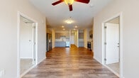 Located at 4416 Belleview Ave in Kansas City, MO, this single-floor unit offers four bedrooms and five bathrooms within a well-designed layout. The open living and kitchen area is anchored by warm hardwood-style flooring, recessed lighting, and a ceiling fan that enhances airflow throughout the expansive common space. The kitchen is equipped with gray shaker-style cabinetry, a stainless steel refrigerator, dishwasher, and range, complemented by a wall-mounted mini-split HVAC unit for efficient climate control. A long hallway connects the living area to the private quarters, where bedrooms feature plush carpeting and neutral tones. Select bedrooms provide direct access to a balcony with outdoor views of surrounding greenery, allowing natural light to fill the space. The bathrooms are clean and functional, with tiled walk-in showers featuring built-in shelving. The primary bedroom offers a private, comfortable retreat. Throughout the unit, white trim, neutral wall colors, and consistent flooring choices create a cohesive and modern aesthetic. The layout is practical and well-proportioned, making this a highly functional multi-bedroom residence suitable for shared living or family occupancy.