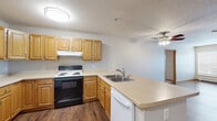 Located at 420 Fifth Ave S in La Crosse, Wisconsin, this well-appointed two-bedroom, one-bathroom unit offers a functional and comfortable single-floor layout. The open-concept kitchen and living area serves as the heart of the home, featuring warm honey-toned cabinetry, a peninsula with a built-in sink, ample counter space, and a full suite of appliances including an electric range and dishwasher. Rich hardwood-style flooring runs throughout the main living areas, complementing the neutral color palette and clean lines of the space. The living room is bright and inviting, with a large window that draws in generous natural light and provides views of the surrounding neighborhood. A ceiling fan adds both comfort and character. The bedrooms are carpeted for warmth, each equipped with a ceiling fan, natural light from windows with blinds, and closet storage — including wood-paneled bi-fold closet doors in the primary bedroom. A flexible den offers additional space ideal for a home office or extra storage. The full bathroom features a tub/shower combo with safety grab bars and hardwood-style flooring. Baseboard heating is present throughout, and the unit also includes a wall-mounted AC unit for year-round comfort.