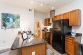 Located at 3225 Pleasant Garden Rd in Greensboro, NC, this single-floor residence offers a well-designed layout with a seamless flow between its main living spaces. The open-concept kitchen is outfitted with warm wood cabinetry, dark granite countertops, a stainless steel island sink, a sleek stainless range hood, and black appliances including an electric range and refrigerator. Track lighting overhead adds both function and style to the space.

The living and dining areas are generously proportioned, featuring polished concrete-style flooring throughout. The living room benefits from a set of French doors that invite natural light, while a dedicated sitting nook provides an intimate space ideal for reading or conversation. Neutral walls throughout create a calm, versatile backdrop.

The primary bedroom is spacious and comfortable, featuring a ceiling fan, natural window light, and ample room for a full bedroom suite. A second bedroom offers similar proportions with its own ceiling fan and natural light. The bathroom includes a tub-shower combination, warm wood vanity cabinetry, dark granite countertops, and an adjacent walk-in closet with built-in shelving. Together, these features make for a practical and inviting living environment.
