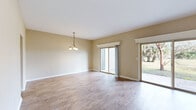 This two-story, 3-bedroom, 3-bathroom home offers a well-organized layout across two floors, combining functional living spaces with classic design details. The main floor features a generous living room with light wood-style flooring, neutral warm-toned walls, and a striking brick fireplace with a raised hearth and white decorative mantle that serves as a central focal point. Two sliding glass doors flood the space with natural light and provide direct access to a patio overlooking a spacious, open yard with mature trees. A staircase from the living area leads to the upper floor. The kitchen is equipped with warm wood cabinetry, white appliances including a range and refrigerator, a double sink, and light tile flooring. A stacked washer and dryer unit is conveniently integrated into the kitchen area, complemented by additional tall storage cabinetry. The three bedrooms feature plush carpeting, ceiling fans with light fixtures, and windows that bring in natural light and outdoor views. Two closets provide dedicated storage. The bathrooms include tub-shower combinations with white tile surrounds. Utility rooms and hallways round out the floor plan, contributing to smooth circulation throughout the home. The overall ambiance is bright, clean, and functional.