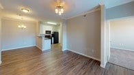 This single-floor unit offers a thoughtfully designed layout that balances comfort and functionality throughout. The living area greets residents at the entry with rich hardwood-style flooring, crown molding, a ceiling fan with light fixture, and a side window that allows natural light to flow through the space. It connects seamlessly to the kitchen, which is equipped with white shaker-style cabinetry, dark countertops, black appliances including a range, microwave, dishwasher, and refrigerator, along with a stainless steel sink. A pendant chandelier adds a touch of elegance to the adjacent dining area.

The bedrooms feature plush wall-to-wall carpeting, ceiling fans with lighting, and windows dressed with horizontal blinds that provide ample natural light and outdoor views. A dedicated laundry closet with wire shelving and utility hookups adds everyday convenience.

The bathroom is highlighted by hardwood-style flooring, a wide vanity with a dark countertop and white under-mount sink, a well-lit mirror, and a tiled shower. A spacious walk-in closet accessible from the bathroom offers multi-level wire shelving and hanging rods, providing generous storage. The overall ambiance is clean, modern, and move-in ready.