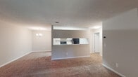 Located at 5300 Woodruff Farm Rd in Columbus, Georgia, this single-floor unit offers a well-organized and functional layout. The open-concept living and dining area is generously sized, featuring warm neutral-toned carpet and a textured ceiling. A chandelier adds a touch of elegance to the dining space, while a pass-through counter connects the living area to the kitchen, creating an airy, connected feel throughout.

The kitchen is designed for practicality, featuring white cabinetry with ample storage, light-toned countertops, a stainless steel sink, and black appliances including a range and refrigerator. Wood-look vinyl flooring runs the length of the kitchen, providing a clean contrast to the surrounding carpeted areas.

The living area opens to the outdoors through a sliding glass door dressed with vertical blinds, offering a view of lush greenery outside. The bedroom is carpeted and includes a ceiling fan with light fixture, as well as a window that allows natural light to filter in.

The bathroom is straightforward and clean, featuring a full tub-and-shower combo with a white surround. Throughout the unit, neutral wall tones and clean white trim create a cohesive, move-in-ready aesthetic that is both practical and welcoming.