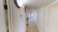 This single-floor residence is designed with an open, functional layout that connects the main living spaces seamlessly. The living room is a standout area, featuring soaring vaulted ceilings, a tile-surround wood-burning fireplace, and a striking arched window that floods the space with natural light. A sliding glass door leads to a private balcony with outdoor views of surrounding trees, enhancing the room's airy feel. The carpeted flooring runs throughout the living areas and bedrooms, contributing to a warm, comfortable atmosphere.

The kitchen is efficiently arranged with wood-accented cabinetry, a full suite of white appliances including a refrigerator, electric range, and dishwasher, plus a stainless steel sink and tile flooring. A peninsula counter with a pendant light overhead connects to the dining area, which also benefits from vaulted ceilings.

The bedrooms are well-proportioned, each featuring carpet, natural light from arched or standard windows, and access to closet space. One bedroom includes a walk-in closet and direct bathroom access. Two bathrooms serve the unit; one features tile flooring with a wood vanity, while the other includes a tub-shower combination with decorative mosaic tile accents and white wall tile throughout.
