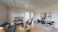 Located at 1431 N Church St in Portland, Oregon, this single-floor residence offers a thoughtfully designed layout with a contemporary aesthetic and light-filled interiors. Light-toned hardwood flooring runs throughout, tying together each area with a cohesive, warm feel.

The open-concept living and dining area is bright and inviting, featuring large windows that frame sweeping views of the Portland skyline and surrounding treetops. The living space accommodates comfortable seating alongside a dedicated dining area, making it well-suited for both relaxing and entertaining.

The kitchen is a standout feature, finished entirely in matte black — from the flat-front cabinetry and dark countertops to the full suite of black appliances, including a refrigerator, range, microwave, and dishwasher. This bold design choice creates a striking contrast against the light flooring.

The bedroom is generously proportioned, wrapped by large windows on two walls that flood the room with natural light and offer expansive views of the neighborhood and distant hills. The bathroom is finished in a clean, minimal style with a full soaking tub and shower combination, dark fixtures, and dark tile flooring.

A hallway with a louvered closet and a round gold-framed mirror connects the private spaces, adding a refined detail to an otherwise sleek and modern interior.