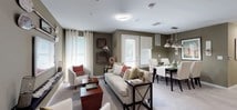 Located at 175 Forest Avenue in Hawthorne, NJ, this single-floor residence offers a well-designed layout that balances comfort and functionality throughout. The open-concept living and dining area serves as the heart of the home, featuring soft carpet flooring, earthy olive-toned walls, and abundant natural light streaming through multiple windows dressed with sheer curtains and blinds. The living room provides generous seating space, while the adjacent dining area is defined by a striking industrial-style pendant light fixture above a dark wood dining table surrounded by upholstered grid-pattern chairs. The kitchen is equipped with sleek dark cabinetry, stainless steel appliances including a gas range, microwave, and refrigerator, complemented by a herringbone tile backsplash, light stone countertops, and wood-look tile flooring. A chalkboard accent wall adds a functional and stylish touch. The primary bedroom is a calm retreat with plush carpet, neutral tones, and multiple windows that fill the room with natural light. A second bedroom offers similar comfort and brightness. A flexible room serves well as a home office or guest space, featuring a daybed and a rustic wooden desk. Two full bathrooms are finished with large-format tile flooring — one featuring a shower-tub combination, the other a glass-enclosed shower and a dark vanity with stone countertops.
