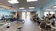 Located at 28 Southfield Ave in Stamford, Connecticut, this fitness center is a comprehensively equipped, single-floor facility designed to support a full range of workout routines. The space is finished with durable rubber flooring throughout, providing both safety and comfort during exercise. Bright flush-panel skylights and recessed ceiling lights ensure the entire area is well-illuminated, complemented by large windows that bring in natural light and offer views of the surrounding cityscape.

The cardio zone features a row of Matrix treadmills, elliptical trainers, and stationary bikes, all positioned near the windows to make the most of the natural light and outdoor views. A dedicated strength training area houses a multi-functional cable machine, a selectorized weight stack, adjustable benches, and a well-stocked dumbbell rack with a variety of weights. Full-length mirrors line multiple walls, visually expanding the space and allowing users to monitor their form during workouts.

A designated functional training section includes stability balls, medicine balls, and foam rollers neatly organized on a SPRI rack, catering to flexibility and core training needs. A wall-mounted flat-screen TV adds a modern touch for entertainment or instructional content. The overall ambiance is clean, modern, and professional, making this fitness center a well-rounded destination for residents and users seeking a complete workout experience.