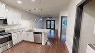 Located at 455 W Sullivan St in Kingsport, TN, this 2-bedroom, 1-bathroom unit offers a thoughtfully designed single-floor layout. The open-concept kitchen and living area serves as the heart of the space, where rich hardwood-style flooring flows seamlessly throughout. The kitchen is outfitted with crisp white shaker cabinets, light granite-style countertops, a central island with a double undermount sink, pendant lighting, and a full suite of stainless steel appliances including a refrigerator with ice maker, range, built-in microwave, and dishwasher. The living room is bright and airy, anchored by a ceiling fan and a set of black-framed French doors that invite natural light and provide outdoor access. Both bedrooms feature plush carpeting, ceiling fans, and windows with exterior views. The primary bedroom includes a closet with wire shelving. The bathroom is clean and functional, offering a tiled tub-shower combination, hardwood-style flooring, and granite-topped vanity. In-unit laundry connections are also present. Neutral tones and modern finishes throughout create a cohesive, move-in ready environment well-suited for comfortable everyday living.