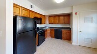 Located at 1 Reler Lane in Franklin Park, NJ, this 2-bedroom, 1.5-bathroom residence offers a practical and comfortable single-floor layout. The kitchen is a standout feature, showcasing warm honey-toned cabinetry, dark granite countertops, and a full suite of black appliances including a gas range, built-in microwave, dishwasher, and refrigerator, all set atop light-toned tile flooring. The entry area also features tile flooring and transitions seamlessly into the carpeted living room, which is bright and open with a sliding glass door leading to a private balcony with outdoor views. Both bedrooms are carpeted and filled with natural light from large windows fitted with blinds. One bedroom includes a sliding closet, while the other offers a generous window overlooking greenery. The full bathroom includes a single-sink vanity with warm wood cabinetry, a combined tub and shower with white tile surround, and mosaic tile flooring. A convenient half-bath provides an additional vanity and toilet. Throughout the unit, the neutral color palette and clean finishes create a bright, move-in-ready atmosphere.