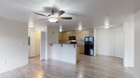 Located at 700 Matzen St in St. Helens, Oregon, this single-floor unit offers a well-designed, open-concept layout that seamlessly connects the living and kitchen areas. Wood-style plank flooring runs throughout the main living spaces, adding warmth and cohesion to the interior.

The kitchen is a standout feature, equipped with warm-toned wood cabinetry extending to the ceiling for generous storage, speckled granite countertops, and black appliances including a refrigerator, electric range, and over-the-range microwave. A peninsula with bar seating serves as both a functional workspace and a casual dining area, connecting the kitchen to the open living space. A double undermount sink is positioned on the peninsula for added convenience.

The living area is bright and open, featuring a ceiling fan with light fixture, a wall-mounted HVAC unit, and access to an exterior door that allows for natural light. Additional rooms include well-proportioned bedrooms with wood-style flooring and natural light from windows with blinds.

The bathrooms are finished with the same granite countertops found in the kitchen, warm wood cabinetry, undermount sinks, large mirrors, and tile flooring. Grab bars and open shelving add both accessibility and practicality. The overall aesthetic is clean, modern, and consistent throughout the unit.