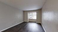 Located at 834 Timberlake Cir in Arlington, TX, this single-story unit offers three bedrooms and two bathrooms across a well-organized floor plan. Dark hardwood-style flooring runs throughout the home, providing a cohesive and polished look in every room.

The living room is a comfortable, open space featuring a large window with blinds that brings in natural light and offers views of the surrounding exterior. The galley-style kitchen is efficiently designed with gray lower and upper cabinetry, white countertops, a subway tile backsplash, and black appliances including a refrigerator and range. A bright overhead light keeps the space well-lit.

The spacious primary bedroom features dark flooring, neutral gray walls, and a dedicated closet. The two additional bedrooms are each equipped with ceiling fans, windows for natural light, and closets, making them versatile spaces suitable for sleeping, working, or other uses. All three bedrooms are connected via a central hallway.

The two bathrooms offer clean, functional layouts. One includes a marble-style vanity countertop with a mirror and window, while the second features a full tub-shower combo with white tile surround. Both maintain a bright, neutral aesthetic consistent with the rest of the home.