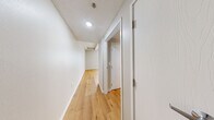 Located at 121 W Poplar in Sidney, Ohio, this single-floor unit offers a thoughtfully arranged layout across a compact but efficient footprint. Warm hardwood-style flooring runs continuously throughout the space, lending a cohesive and inviting feel to every room.

The main living area is open and bright, with neutral gray walls, clean white baseboards, and a large window that invites natural light and outdoor views. Structural beam details along the ceiling add a subtle architectural character to the room.

The kitchen is positioned adjacent to the living area and features warm wood cabinetry, a white countertop peninsula that doubles as a casual dining or prep surface, a stainless sink, and a range. The peninsula layout creates a natural visual boundary between the kitchen and living space while maintaining an open, connected feel.

A hallway connects the main living area to the bathroom, which is clean and functional, featuring a toilet, grab bar, and a shower area, all finished with the same light hardwood-style flooring. The bright, white walls and ceiling lighting keep the space feeling fresh and well-lit.

Overall, the unit presents a clean, move-in-ready aesthetic with practical finishes suitable for everyday living.
