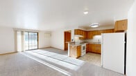Located at 1415 Silverstone Trl in De Pere, Wisconsin, this single-floor, 2-bedroom, 2-bathroom home offers a practical and comfortable layout. The open-concept kitchen and living area serves as the heart of the home, featuring warm oak cabinetry, a peninsula with counter seating, tile flooring, and white appliances including a refrigerator and range. The adjoining living area is carpeted and filled with natural light streaming through a large sliding glass patio door with vertical blinds, providing outdoor views and easy access to the exterior.

Both bedrooms are carpeted and well-lit, each featuring a ceiling fan with light fixture and wood-trimmed windows that allow in ample natural light. The generously sized primary bedroom includes a walk-in closet outfitted with built-in shelving and hanging rods. The two bathrooms are finished with tile flooring and oak vanity cabinetry; one includes a tub-shower combination, while the other features a standalone glass-enclosed shower stall. Warm wood-tone trim and door frames carry consistently throughout the home, lending a cohesive aesthetic. The attached garage offers additional utility with a built-in overhead shelf and an automatic garage door opener, rounding out this well-appointed home.