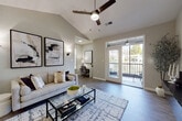 This single-floor residence is thoughtfully designed with a neutral palette of warm greige tones, wood-look flooring, and white trim throughout, creating a cohesive and contemporary aesthetic. The entryway introduces the space with an artful wall display and leads into the main living areas.

The living room is a standout, featuring soaring vaulted ceilings with a ceiling fan, wall sconces, and French doors that open directly onto a private balcony furnished for outdoor enjoyment. A dedicated workspace is seamlessly integrated into the living area, adding functional versatility.

Adjacent to the living room, the dining area features crown molding, chair rail detailing, wood-look flooring, and a pendant light fixture overhead, offering a refined setting for meals.

The kitchen is a galley-style layout equipped with white cabinetry, dark granite-style countertops, and stainless steel appliances. It connects directly to a dedicated laundry area with a full-size washer and dryer.

Two bedrooms are carpeted for comfort, each with ceiling fans and generous natural light from large windows dressed with sheer curtains. The bathroom includes a full tub-shower combination with clean white finishes and wood-look flooring.