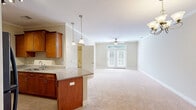 Located at 42 Senator Reynolds Rd in Woodfin, NC, this well-appointed one-bedroom, one-bathroom residence offers a thoughtfully designed single-floor layout with a comfortable sense of space throughout. The open-concept kitchen flows seamlessly into the living room, creating an inviting, connected living area. The kitchen is outfitted with warm-toned wood cabinetry, granite countertops, black appliances including a refrigerator, range, and dishwasher, and tile flooring. Pendant lighting and track lighting add functional style, while crown molding lends a polished finish. The living room features soft carpeting, a ceiling fan, and French doors that open to a private balcony, allowing natural light to fill the space. The generously sized bedroom includes plush carpet, a ceiling fan, and two closets, providing ample storage. The bathroom is clean and functional, featuring a granite-topped vanity, tile flooring, and a full tub-shower combination. A dedicated laundry room with full-size washer and dryer hookups and overhead cabinetry adds practicality. Neutral wall tones and consistent finishes throughout create a cohesive and welcoming atmosphere.