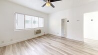 Located at 5940 San Fernando Rd in Glendale, CA, this one-bedroom, one-bathroom unit offers a thoughtfully designed single-floor layout that maximizes its compact footprint. Light wood-look flooring flows consistently throughout all rooms, creating a cohesive and clean aesthetic.

The kitchen is a standout feature, equipped with white cabinetry, granite-style countertops, a stainless steel gas range, and a bold mosaic tile backsplash in earth tones of brown, beige, and cream. A double-basin stainless steel sink adds functionality to the space.

The bedroom features mirrored sliding closet doors, a ceiling fan, a wall-mounted air conditioning unit, and a built-in heating panel with a digital thermostat. Horizontal windows positioned near the ceiling allow natural light to enter while maintaining privacy.

The bathroom is finished with wood-look tile flooring, white cabinetry topped with a warm mosaic tile countertop, a large black-framed mirror, and a full tub-shower combination. A window above the tub provides ventilation and additional natural light.

A hallway connects the rooms, contributing to an efficient and functional flow throughout the unit. The overall design palette is bright and neutral, emphasizing clean lines and modern finishes.