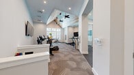 Located at 40 Hathaway Ln in Lebanon, TN, this fitness center offers a thoughtfully designed exercise space that combines architectural character with practical functionality. The room's most striking architectural feature is its soaring vaulted ceiling, adorned with rustic whitewashed wood planking and dual ceiling fans that enhance both airflow and aesthetic appeal. Recessed lighting throughout ensures the space is well-lit at all times, complemented by large windows that invite natural light and provide outdoor views.

The main exercise area is finished with durable geometric-patterned carpet tile, providing both comfort underfoot and a modern visual element. The cardio zone is well-stocked with True-brand treadmills, elliptical trainers, and a stair climber, each equipped with individual display consoles. Wall-mounted flat-screen televisions are positioned throughout for entertainment during workouts. An Echelon rowing machine adds to the range of cardio options available.

A dedicated functional training alcove houses stability balls, a weight bench, and additional strength equipment, separated from the main floor for focused training sessions. A mirrored strength area with free weights and a wall-mounted hydration station round out the amenities. The clean, white wall palette keeps the space feeling open and energizing, making this fitness center a comprehensive and inviting facility.