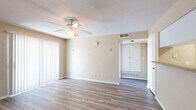 Located at 1512 Hollowhill Dr in Bryan, Texas, this single-floor residence offers a well-organized layout designed for comfortable everyday living. The main living area features light wood-look laminate flooring, neutral beige walls, a textured ceiling, and a ceiling fan with integrated lighting. Vertical blinds cover a sliding glass door, allowing natural light to filter through while providing privacy. The kitchen is equipped with white cabinetry, a white electric range, over-the-range microwave, dishwasher, and a full-size refrigerator tucked into a dedicated alcove. A peninsula counter separates the kitchen from the adjacent dining area, which is accented by a pendant light fixture overhead. The entryway provides convenient access to a coat closet and a utility closet with washer/dryer connections. The bedrooms feature plush carpeting, ceiling fans, and ample closet space, with windows that invite natural views of the surrounding greenery. The bathroom includes a full tub-shower combination with white tile surround, a toilet, and a built-in shelving unit accessible from the hallway. Throughout, the home maintains a clean, neutral palette that offers a versatile canvas for personalization.