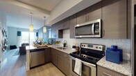 Located in Tampa, FL, this thoughtfully designed residence offers a seamless open-concept floor plan that connects the kitchen, dining, and living areas into one cohesive living space. The contemporary kitchen is a standout feature, equipped with stainless steel appliances including a range, microwave, and dishwasher, complemented by rich dark wood cabinetry, granite countertops, a classic subway tile backsplash, and pendant lighting overhead. Light wood-style flooring flows throughout the main living areas, enhancing the bright, airy atmosphere. The living room features a bold accent wall in a deep slate blue, creating a stylish focal point, while large windows and sliding glass door access to an outdoor balcony invite abundant natural light. The bedroom is a serene retreat finished with plush carpet, multiple windows, and ample natural light. The bathroom mirrors the kitchen's refined aesthetic with matching dark wood cabinetry, granite countertops, dual mirrors, and clean tile flooring. Louvered closet doors and recessed lighting add functional elegance throughout. Situated in the heart of Tampa near North Meridian Avenue, this residence combines modern finishes with a practical layout ideal for contemporary urban living.