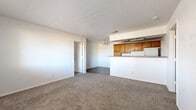 Located at 1022 E Narramore Ave in Buckeye, Arizona, this single-story home offers a well-organized layout with two bedrooms, two bathrooms, a kitchen, and a utility room. The galley-style kitchen is equipped with warm oak cabinetry, a double sink, electric range, dishwasher, and refrigerator. Countertops provide ample prep space along both sides of the kitchen, which features durable dark hardwood-style flooring that extends into the bathrooms. A peninsula counter connects the kitchen to the adjacent living area, creating an open, functional transition between spaces. The living area is finished with neutral carpet and includes a ceiling fan overhead. Both bedrooms are carpeted and fitted with ceiling fans, offering a comfortable and consistent feel. Each bedroom benefits from natural light via windows with horizontal blinds, with exterior views of the surrounding neighborhood. The two bathrooms mirror each other in design, each featuring a warm wood vanity with a single sink, framed mirror, shower/tub enclosure with sliding glass doors, and dark hardwood-style flooring. A dedicated utility room provides additional functional space. Overall, the home presents a clean, straightforward design suited for everyday living in the Buckeye community.