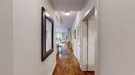 Located in Houston's vibrant Montrose neighborhood, this thoughtfully designed 2-bedroom, 2-bathroom residence offers a seamless blend of modern finishes and comfortable living. Rich hardwood floors extend throughout the main living areas, lending warmth and continuity to the open-concept floor plan. A welcoming hallway leads into the heart of the home, where the living, dining, and kitchen spaces flow naturally together. The kitchen is a standout feature, boasting rich dark wood cabinetry, a white quartz island with bar seating, stainless steel appliances, a subway tile backsplash, and track lighting that highlights every detail. The dining area accommodates a full dining setup and connects seamlessly to the living room, which is anchored by a ceiling fan and ample natural light. The spacious primary bedroom features plush carpeting, a ceiling fan, floor-to-ceiling glass doors overlooking lush greenery, and a serene, well-lit ambiance. The second bedroom provides comfortable accommodations, while both bathrooms are finished with granite countertops and tile flooring. Additional features include a dedicated closet and hallway that enhance the efficient layout. This residence offers refined urban living in one of Houston's most sought-after locations.