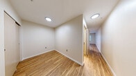 Located at 219 E Garfield St in Seattle's Capitol Hill neighborhood, this efficiently designed unit offers a practical single-floor layout comprising a kitchen, bathroom, and hallway connecting to an open living area. Throughout the space, warm wood-look plank flooring creates a cohesive and inviting aesthetic.

The kitchen is well-appointed with stainless steel appliances, including a full-size refrigerator, electric range with hood ventilation, and dishwasher. Cabinetry features a two-tone design — crisp white upper cabinets paired with soft gray lower cabinets — complemented by light countertops and a built-in sink, maximizing both storage and functionality within a compact footprint.

The bathroom offers a clean, contemporary finish with large-format tile surrounding a soaking tub and shower combination, a wall-mounted shower rod, and a vanity unit with gray shaker-style cabinetry, a white countertop, and a frameless mirror above. Wood-look flooring continues here, tying the space together.

The hallway provides a smooth transition between rooms and leads to the main living area, which features neutral warm-toned walls, a window allowing natural light to filter in, and a closet for added storage. The open layout and consistent finishes throughout give the space a clean, modern character well-suited to urban living in Seattle.