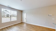 Located at 4775 Dublin Road in Columbus, Ohio, this one-bedroom, one-bathroom unit offers a well-designed single-floor layout with a clean, modern aesthetic. The open-concept kitchen and living area serves as the heart of the home, featuring light-toned luxury vinyl plank flooring, warm pendant lighting over a central island, and a bright front entry door with a sidelite window that invites natural light. The kitchen is outfitted with crisp white shaker cabinetry extending to the ceiling, granite countertops, a single-basin sink, and a full suite of stainless steel appliances including a refrigerator, electric range, and built-in microwave. The living area is bathed in natural light through large windows with views of the surrounding community. The bedroom is carpeted for comfort, featuring dual windows that provide generous daylighting and neighborhood views, along with access to a dedicated walk-in closet equipped with wire shelving and hanging rods. The bathroom includes durable LVP flooring and a glass-enclosed shower with sleek black framing. Neutral warm-beige walls and white trim carry throughout, lending a cohesive and move-in-ready feel. The unit also includes an in-unit washer, and the property offers convenient surface parking with landscaped surroundings.