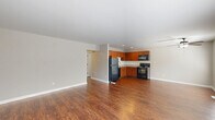 Located at 5303 Rue De Ville in Indianapolis, Indiana, this single-floor, 2-bedroom, 1-bathroom home offers a practical and comfortable layout. The open living room greets you with rich, warm hardwood-style flooring, multiple windows, and a ceiling fan, creating a bright and welcoming atmosphere. The adjacent kitchen is well-appointed with warm wood cabinetry, light granite-style countertops, and a full suite of black appliances including a refrigerator, range, and over-the-range microwave — all set atop matching hardwood-style flooring. A second living or dining area features plush carpeting and sliding glass door access to an outdoor patio, bringing in natural light and a seamless indoor-outdoor connection. Both bedrooms are carpeted for comfort, each featuring generous built-in closets with louvered bifold doors for ample storage. The spacious primary bedroom offers vaulted ceiling details and abundant closet space, while the second bedroom includes a large window with views of the surrounding area. The full bathroom is clean and functional, complete with a full tub-shower combo and brushed nickel fixtures. A connecting hallway ties the layout together efficiently, making this home a well-organized and inviting residence.