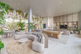 Located at 3775 Sixth Avenue in San Diego's Hillcrest neighborhood, this thoughtfully designed communal lounge space offers a sophisticated and inviting atmosphere across a single open floor. The layout is anchored by a sweeping, curved sectional sofa positioned atop a woven area rug, complemented by additional built-in seating areas integrated with lush, live planters that introduce a fresh, biophilic element throughout the room.

A dramatic floor-to-ceiling tropical mural serves as the space's defining focal point, depicting lush banana leaves, exotic wildlife, and botanical scenes in rich, vibrant detail. The mural sets a warm, resort-inspired tone that carries throughout the entire interior. Recessed lighting and smooth, light-toned ceilings keep the ambiance bright and refined.

A natural wood billiards table occupies a central zone, adding a recreational dimension to the space. Adjacent to it, a built-in shelving and entertainment wall in warm wood tones houses a flat-screen display, providing a media-ready lounge area. A curved bar counter with stylish seating adds a social gathering spot near the mural wall.

Large, floor-to-ceiling windows along one side flood the space with abundant natural light and offer views of the surrounding outdoor greenery, further reinforcing the nature-inspired design ethos. Light stone tile flooring ties all zones together seamlessly, creating a cohesive and polished environment ideal for socializing and relaxation.
