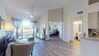 Located at 244 Three Islands Blvd in Hallandale Beach, Florida, this single-floor residence offers a thoughtfully designed layout that emphasizes open living and natural light. The main living area is anchored by soaring vaulted ceilings and wood-look flooring, creating an airy, spacious feel. A ceiling fan overhead and a sliding glass door leading to a private balcony complete the room, with outdoor views of the surrounding waterway visible from multiple vantage points.

The kitchen features white cabinetry with light stone-toned countertops, a full suite of appliances, and a pass-through peninsula that connects seamlessly to the living and dining areas. A separate laundry area is conveniently accessible from within the kitchen.

The primary bedroom is generously sized with vaulted ceilings, a ceiling fan, sliding balcony access with water views, and plush carpeting. A walk-in closet and a full en-suite bathroom with a soaking tub and single vanity complete this retreat. A second bedroom also includes carpeting, ample closet space, and its own access to a bathroom featuring a well-lit vanity and light wood-look flooring. The overall ambiance is bright, coastal, and welcoming throughout.