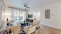 The Derby Model is a thoughtfully designed 4-bedroom, 2-bathroom residence located in Royal Palm Beach, Florida. The single-floor layout makes efficient use of space, seamlessly connecting the main living areas for a cohesive, functional flow. Light wood-look flooring runs throughout the main areas, complementing the bright, neutral color palette.

The open kitchen is a standout feature, equipped with stainless steel appliances, a subway tile backsplash, abundant light gray cabinetry extending to the ceiling, and a white-topped island that doubles as a casual dining spot. Adjacent to the kitchen, the dedicated dining area offers additional space for formal meals, positioned conveniently near a full bathroom.

The living room is bright and welcoming, with a ceiling fan, sliding glass doors that open to a private balcony with tropical views of palm trees, and ample space for comfortable seating arrangements.

The primary bedroom features plush carpeting, a ceiling fan, a window framing lush outdoor greenery, and dual closets accessible via a dedicated hallway, providing generous storage. The two bathrooms are clean and modern, each featuring a tub-shower combination with white subway tile surrounds, contemporary vanities, and LED-lit mirrors. The additional bedrooms maintain the same comfortable, well-lit aesthetic throughout.