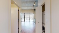 Located at 618 S Main St in the heart of Ann Arbor, MI, this studio unit delivers an urban industrial aesthetic with thoughtful functionality. The open-plan layout is defined by striking exposed concrete ceilings with visible ductwork and track lighting, warm hardwood flooring, and a combination of painted and raw concrete accent walls that lend the space a distinctive loft character.

The kitchen is well-appointed with warm wood cabinetry, dark granite countertops, and a full suite of stainless steel appliances including a range, over-the-range microwave, dishwasher, and refrigerator. A wine rack integrated into the upper cabinetry adds a practical design touch. The open kitchen flows naturally into the main living area, which benefits from large floor-to-ceiling windows with slatted blinds that allow ample natural light while maintaining privacy.

The bathroom features wood-toned cabinetry with a dark countertop vanity, and a tiled walk-in shower with classic subway tile walls. A stacked in-unit washer and dryer is conveniently tucked behind a closet panel, adding everyday practicality to the compact footprint. The overall ambiance is modern and industrial, with clean lines and durable finishes throughout.