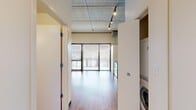 Located at 618 S Main St in the heart of Ann Arbor, MI, this studio unit delivers an urban industrial aesthetic with thoughtful functionality. The open-plan layout is defined by striking exposed concrete ceilings with visible ductwork and track lighting, warm hardwood flooring, and a combination of painted and raw concrete accent walls that lend the space a distinctive loft character.

The kitchen is well-appointed with warm wood cabinetry, dark granite countertops, and a full suite of stainless steel appliances including a range, over-the-range microwave, dishwasher, and refrigerator. A wine rack integrated into the upper cabinetry adds a practical design touch. The open kitchen flows naturally into the main living area, which benefits from large floor-to-ceiling windows with slatted blinds that allow ample natural light while maintaining privacy.

The bathroom features wood-toned cabinetry with a dark countertop vanity, and a tiled walk-in shower with classic subway tile walls. A stacked in-unit washer and dryer is conveniently tucked behind a closet panel, adding everyday practicality to the compact footprint. The overall ambiance is modern and industrial, with clean lines and durable finishes throughout.