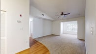 Located at 1007 Fairwinds Cir in Plant City, Florida, this single-story home offers a well-organized layout with a seamless flow between living, dining, and kitchen areas. The open living and dining space is highlighted by vaulted ceilings, a ceiling fan with light fixture, and a large window that draws in natural light. Warm wood-look flooring transitions gracefully into plush carpet throughout the living and bedroom areas. A stylish chandelier anchors the dining area, which opens to a pass-through kitchen counter, creating a connected and functional entertaining space. The kitchen is equipped with light wood cabinetry, granite-look countertops, a white electric range, and a dishwasher, all complemented by a range hood overhead. Two full bathrooms feature light wood vanities with granite-look countertops, wood-look flooring, and tub-shower combinations. The bedrooms are generously sized with soft carpet flooring and ample natural light from windows with blinds. Built-in closets provide practical storage throughout. The overall palette of crisp white walls and light wood tones creates a bright, clean, and inviting atmosphere throughout this well-appointed single-floor home.