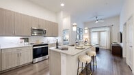Located in San Antonio's desirable Stone Oak neighborhood, this thoughtfully designed 2-bedroom, 2-bathroom residence delivers a refined living experience through modern finishes and a well-planned layout. The open-concept kitchen is a standout feature, showcasing light wood cabinetry, a marble-style tile backsplash, stainless steel appliances, and a granite-topped island with bar seating illuminated by elegant pendant lights. The kitchen flows seamlessly into the living room, where soaring ceilings, wood-style flooring, and a ceiling fan enhance the sense of openness and comfort. Natural light pours in through large windows and a glass patio door. The primary bedroom is a serene retreat with generous proportions, large windows, and an en-suite bathroom featuring a granite vanity, wood-tone cabinetry, and a glass-enclosed shower. The second bedroom is bright and well-sized, served by a full bathroom with a soaking tub and marble-style tile surround. Four closets, including walk-in storage with built-in shelving, offer exceptional organization. A dedicated laundry area, pantry, utility room, and hallway round out the functional interior. The private patio opens to a fenced yard area, providing an inviting outdoor retreat within the community.