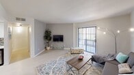 This well-appointed single-floor residence offers a thoughtfully designed layout with a clean, modern aesthetic throughout. The living room is generously sized, featuring light wood-style flooring, neutral tones, and a large sliding glass door that floods the space with natural light and provides access to an outdoor area. The open-concept kitchen is a standout, boasting sleek dark cabinetry, a striking white quartz countertop island, a built-in induction cooktop, stainless steel appliances, and a skylight that adds an airy feel. The adjacent dining area comfortably accommodates a full dining set and includes a ceiling fan and natural light from a side window. The primary bedroom is spacious and bright, with multiple windows allowing ample natural light, light flooring, and a relaxed, comfortable atmosphere. A second bedroom serves well as a guest room or home office, featuring a window and cozy layout. Two full bathrooms are present — one with a glass-enclosed shower, vanity, and a clean white finish, and another conveniently located near the in-unit stacked laundry. Light wood-style flooring runs consistently throughout the main areas, contributing to the home's cohesive, contemporary feel.