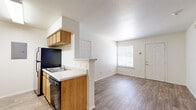 This single-story residential unit offers a practical and well-organized layout designed for comfortable everyday living. The heart of the home is an open-concept kitchen and living area, where warm-toned wood-look flooring extends throughout, creating a cohesive and inviting atmosphere. The kitchen features light oak cabinetry with ample storage, a white countertop peninsula with a built-in sink, and black appliances including a range and refrigerator, all beneath a textured ceiling. The living area is bright and open, benefiting from natural light streaming through a window fitted with white blinds, and includes a ceiling fan for added comfort. A dedicated dining or flex space adjacent to the kitchen also features a ceiling fan and continues the wood-look flooring. The bedrooms are carpeted for warmth and comfort, each offering generous proportions. The primary bedroom includes a wide sliding-door closet, a ceiling fan, and a window that allows natural light. Additional rooms provide versatile spaces suitable for various needs. The bathroom is clean and functional, featuring a full-size soaking tub with a shower surround. Throughout the unit, white six-panel doors, neutral white walls, and consistent finishes contribute to a clean, move-in-ready aesthetic.
