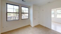 This single-floor residence features two bedrooms, two bathrooms, and a practical, well-organized layout. The kitchen is a standout space, outfitted with dark espresso cabinetry, granite-style countertops, and black and stainless steel appliances including a refrigerator, range, and built-in microwave. Light wood-style flooring runs throughout the kitchen and main living areas, lending a clean, contemporary feel.

The living area benefits from multiple large windows with grid-style frames, allowing generous natural light and outdoor views of surrounding greenery. One bedroom continues this bright character with multiple windows and light hardwood-style flooring, while the second bedroom features neutral carpeting and a window with blinds offering a leafy exterior view.

Both bathrooms are finished with matching granite-topped dark vanities and tiled tub/shower combinations. One bathroom includes accessibility-friendly grab bars throughout the tub area and a bath seat, making the space inclusive and accommodating. The overall design is clean and neutral, with white walls and consistent finishes creating a cohesive, move-in-ready environment throughout.