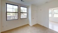 This single-floor residence features two bedrooms, two bathrooms, and a practical, well-organized layout. The kitchen is a standout space, outfitted with dark espresso cabinetry, granite-style countertops, and black and stainless steel appliances including a refrigerator, range, and built-in microwave. Light wood-style flooring runs throughout the kitchen and main living areas, lending a clean, contemporary feel.

The living area benefits from multiple large windows with grid-style frames, allowing generous natural light and outdoor views of surrounding greenery. One bedroom continues this bright character with multiple windows and light hardwood-style flooring, while the second bedroom features neutral carpeting and a window with blinds offering a leafy exterior view.

Both bathrooms are finished with matching granite-topped dark vanities and tiled tub/shower combinations. One bathroom includes accessibility-friendly grab bars throughout the tub area and a bath seat, making the space inclusive and accommodating. The overall design is clean and neutral, with white walls and consistent finishes creating a cohesive, move-in-ready environment throughout.