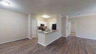 This single-story residence is thoughtfully designed with a cohesive blend of modern finishes and functional layouts. The open-concept kitchen serves as a central hub, featuring white shaker-style cabinetry with brushed nickel hardware, granite countertops, and stainless steel appliances including a range, microwave, and refrigerator. A peninsula with additional granite countertop space extends into the living area, providing a natural transition between the kitchen and the main living space.

The living and dining areas are finished with durable wood-look plank flooring and accented by crown molding, contributing to a polished, cohesive aesthetic. Ceiling fans with light fixtures are present throughout, and vertical blinds allow for natural light control.

The bedrooms are carpeted for comfort, each offering natural light through window blinds and access to closet space. The rooms maintain a neutral color palette that lends versatility to the space.

The bathrooms are well-appointed, featuring granite-topped vanities with white cabinetry, large mirrors, and tiled tub-shower combinations with accent tile detailing. Wood-look flooring carries through the bathrooms, maintaining visual consistency across the unit.